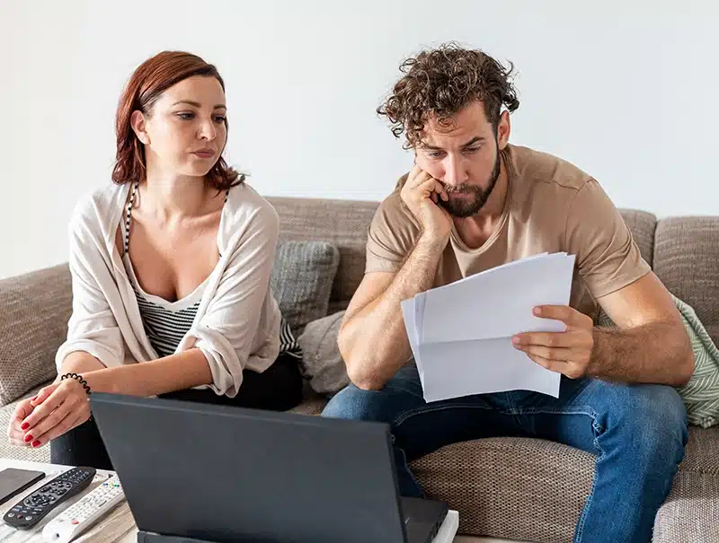 Frustrated couple reviewing denied insurance claim paperwork