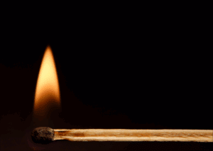 Close-up of a lit match against a dark background