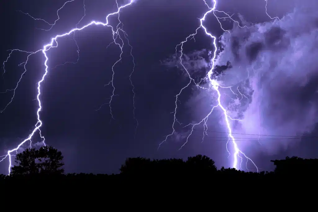 Multiple lightning bolts flashing across a dark stormy sky at night