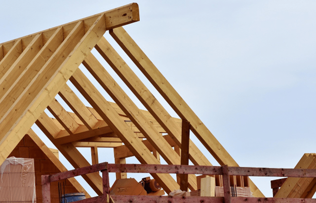 Wooden roof frame under construction against a pale sky