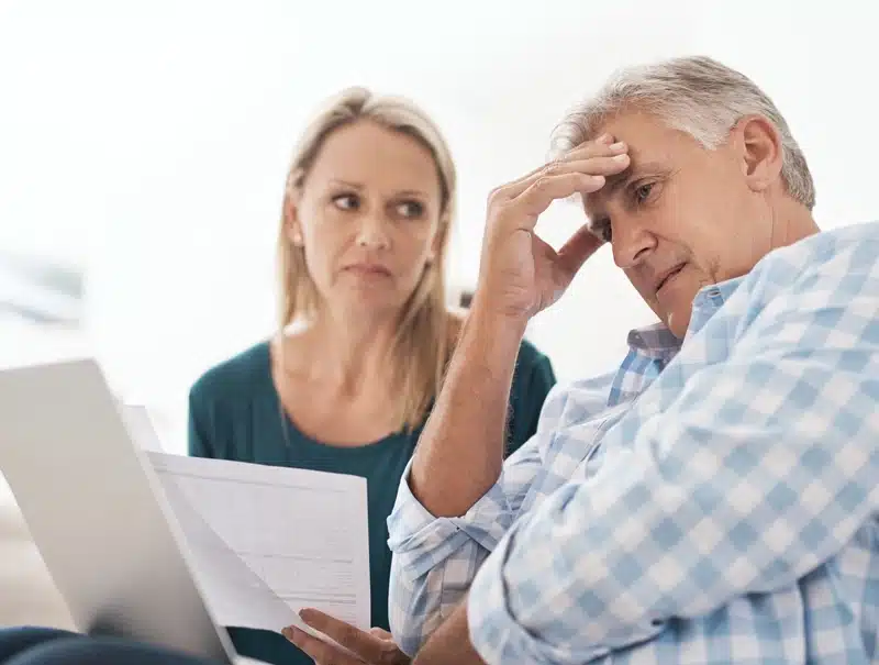 Concerned homeowners reviewing insurance claim paperwork after property damage