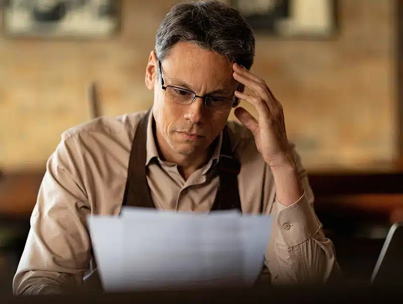 Small business owner stressed while reviewing insurance paperwork