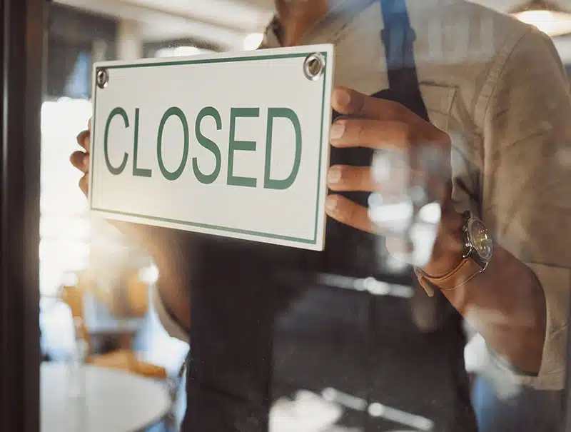 Business owner placing a “Closed” sign on the front door after property damage