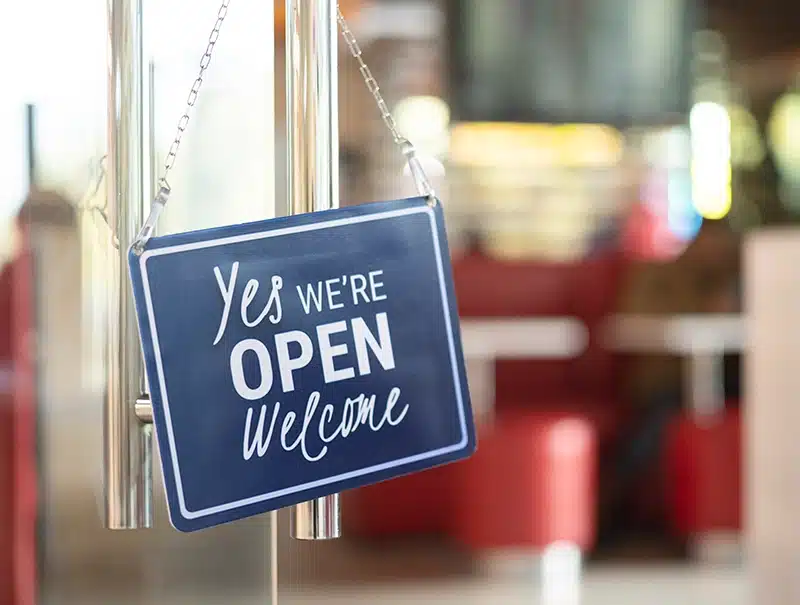 “Yes, We’re Open” sign on a storefront door after business recovery