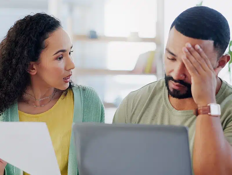 Frustrated homeowners reviewing paperwork after a frozen pipe insurance claim denial.