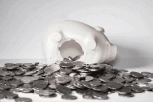 White piggy bank tipped over with coins spilling out.