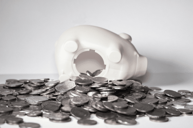 White piggy bank tipped over with coins spilling out.