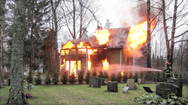 Firefighter extinguishing flames in a burning house.