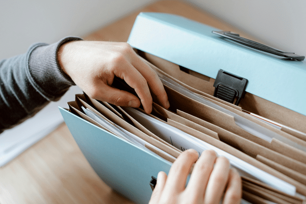 Person organizing documents in a file folder for an insurance claim.