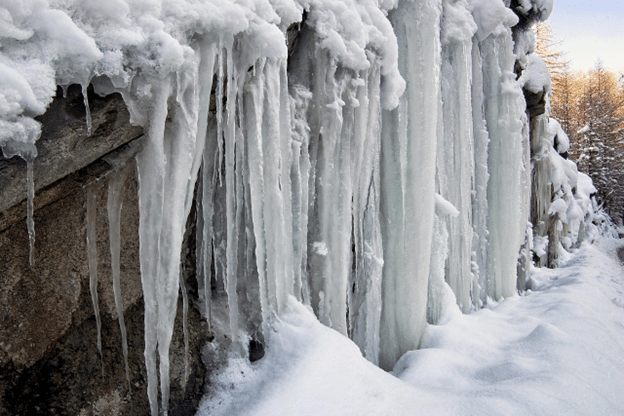 Large icicles hanging from a snow-covered roof edge.