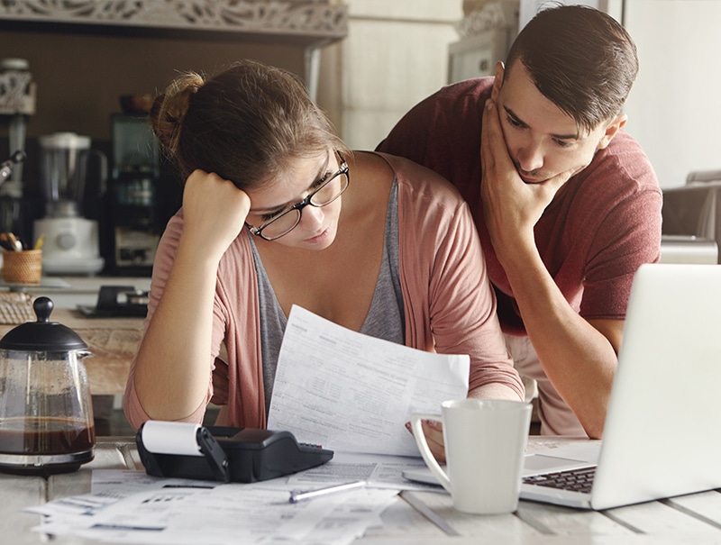 Concerned couple reviewing insurance paperwork at home.