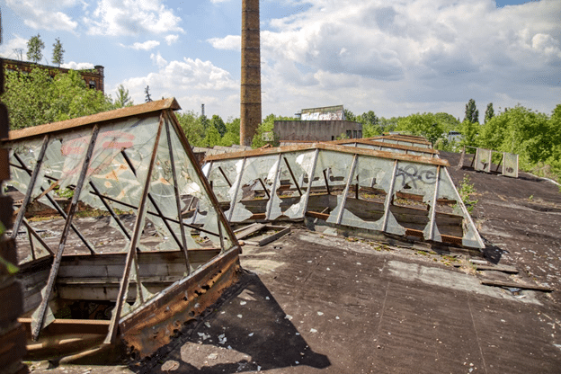 Severely damaged commercial roof with broken skylights and storm-related deterioration.