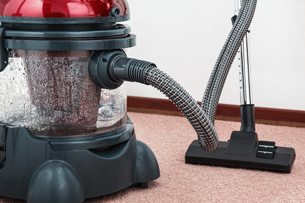Wet vacuum extracting water from soaked carpet after indoor water damage.